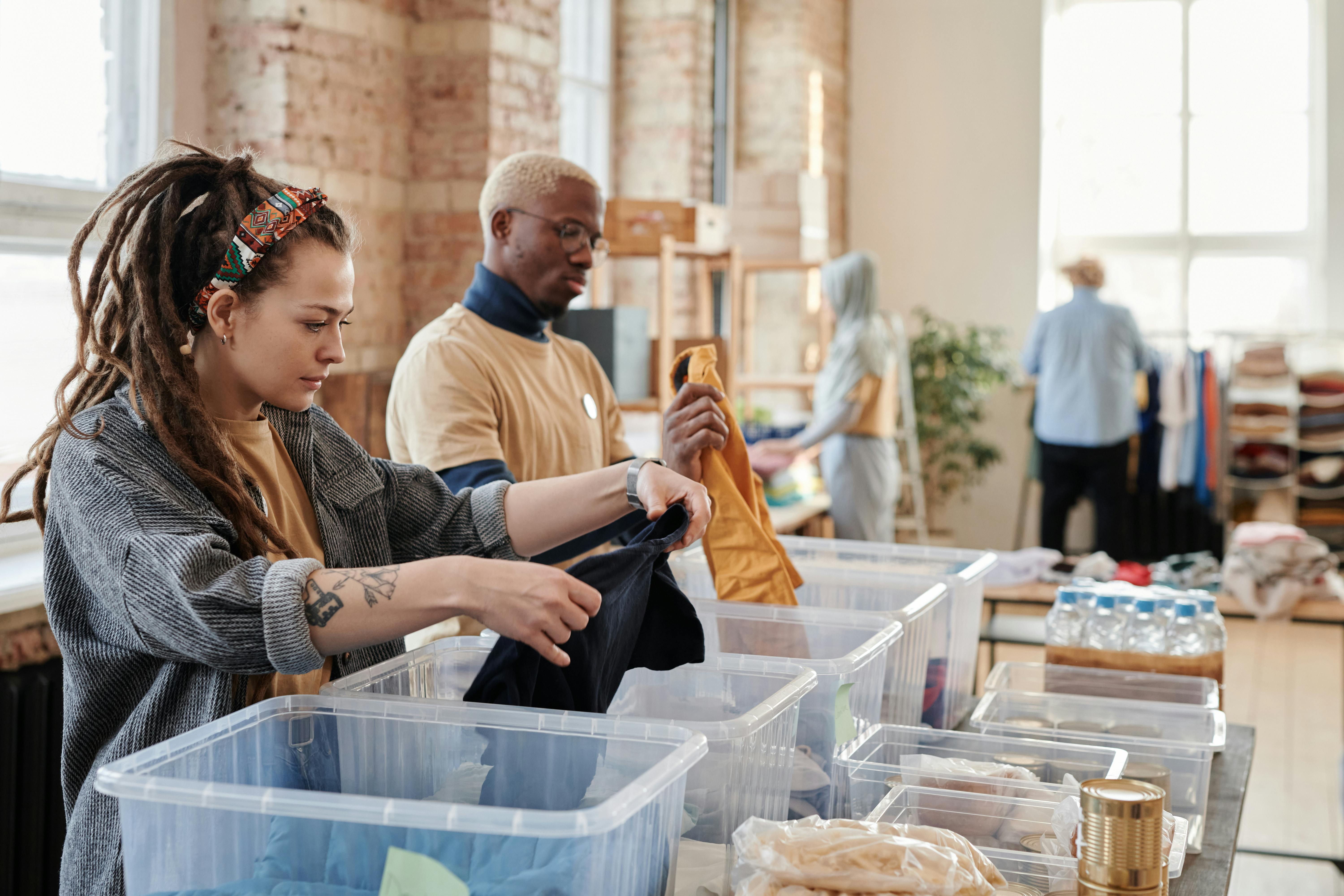 Volunteers Sorting Donations - Two volunteers organizing clothing donations in clear bins at the resale store